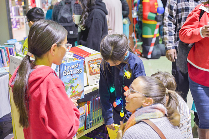 In this Dec. 5, 2024, photo, guests pick out free books from the Zollinger Library booth during Holiday in New Mexico at The University of New Mexico-Gallup.