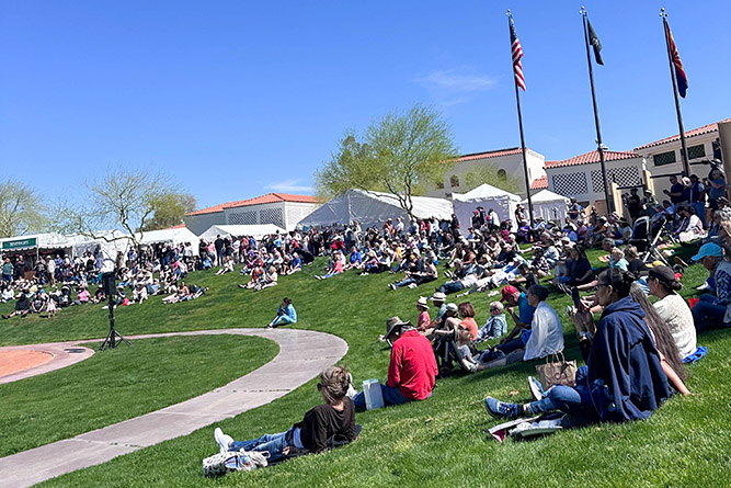 A crowd of spectators sit on the grass in front of the Heard Museum in Phoenix on Saturday, March 7, 2026.