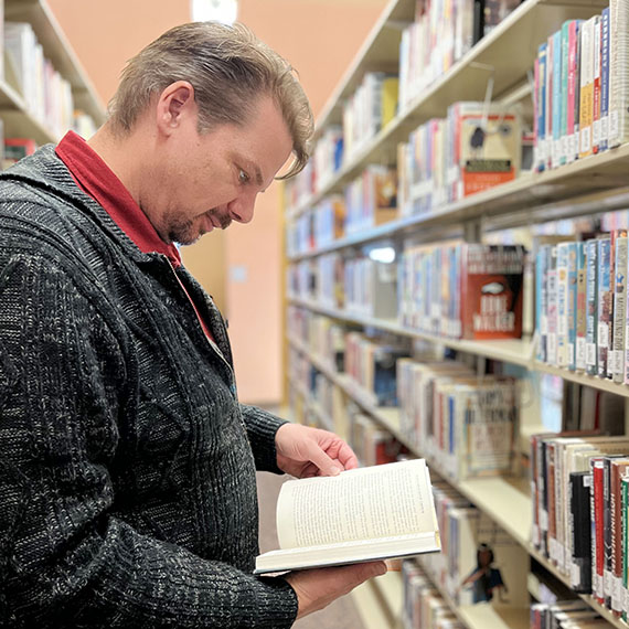 John Zimmerman, chair of the Fine Arts, Humanities and Social Sciences Division, browses through the books of the new Native American Studies section at the Zollinger Library on The University of New Mexico-Gallup campus Thursday, Nov. 3.